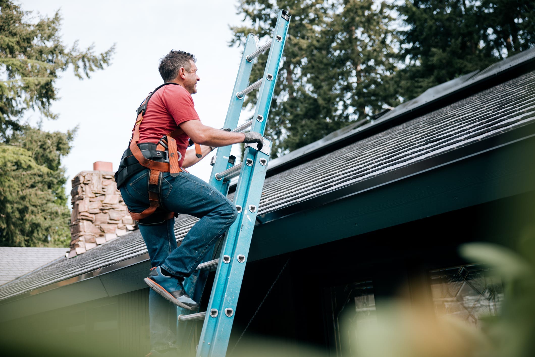 Man climbing a ladder to inspect a roof.
